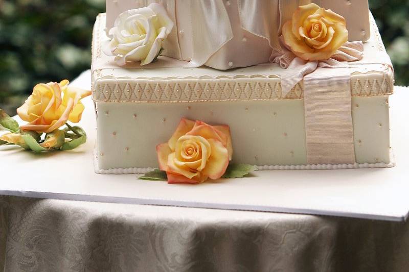 Ana Parzych Custom CakeMulti-shaped tiers adorned with sugar ribbons, pressed lace, textured fondant, piped gold beads, fondant pearls and sugar yellow roses & leaves.