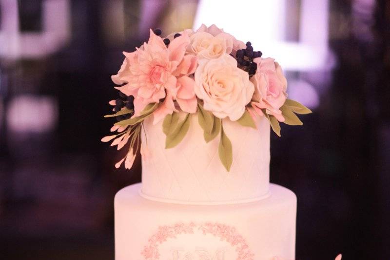 Ana Parzych Custom CakeQuilted fondant tiers with custom monogram plaque and piped pink detail.Features a bouquet of hand-crafted sugar flowers: dahlias, garden roses, peonies, blueberries and leaves.