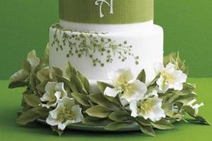 Ana Parzych Custom Cakes Round butter cream and Swiss fondant finished white tiers featuring delicate embroidery green piping, textured fondant band with monogram and embellished with a ring of hand-crafted sugar flowers and leaves.