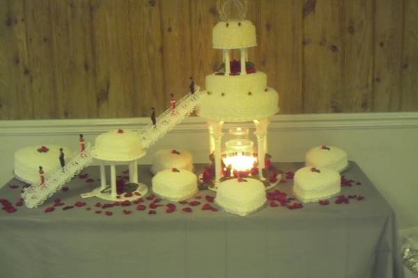 Nine tiers of heart shape cakes of various sizes with columns, double staircases and fountain. Rose petals sprinkle around cakes.