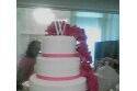 Round,four tiers with pink flowers cascading down the right side and pink ribbon borders