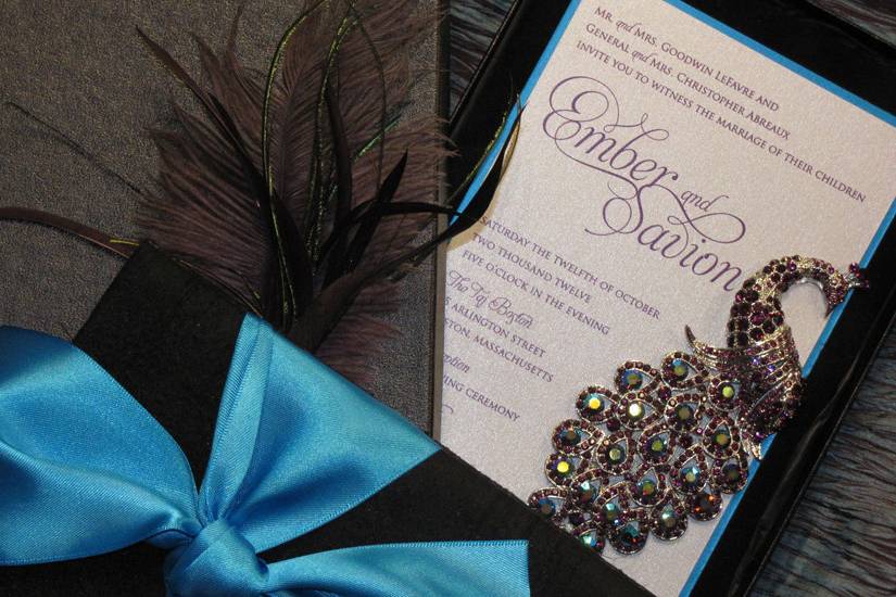 Our couture ensembles are custom created to showcase the theme and design style of your event, while reflecting your personal style and taste.  Shown here, a luxury invitation in peacock theme, with jeweled brooch, layers of silk and velvet, and real peacock feather on the invitation box.
