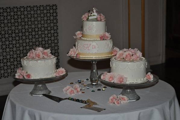 This wedding cake presentation was comprised of a single cake for each of the 12 plus guest tables.  Pictured is near the head table.  All cakes were iced and decorated in buttercream icing.