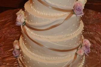 Large 6 tier wedding cake iced in buttercream with fondant draping and real ribbon and flowers.