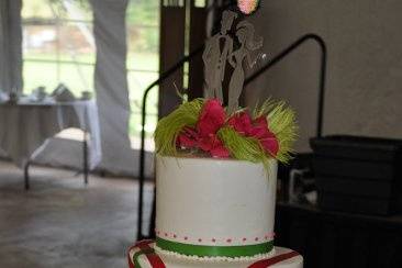 This chic wedding cake was iced in buttercream, accented with real ribbon and garnished with feathers and flowers.