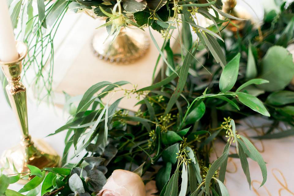 The sweetheart table was adorned with a cascading floral garland, gold flatware and a table linen with gold hand calligraphy with Jack Johnson song lyrics.