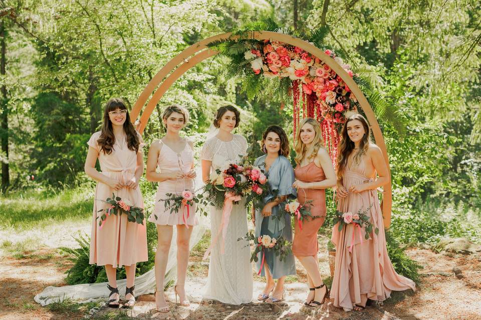 Bride and her bridesmaids by the arch