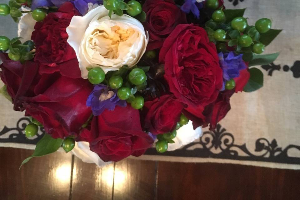 Red and white David Austin Roses, freedom red roses, green hypericum berries, blue delphiniums, and purple chicks