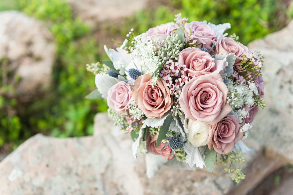 Amnesia Roses, White Ranunculus, lavender wax flower, queen anne’s lace, seeded eucalyptus, and dusty miller, blue thistle