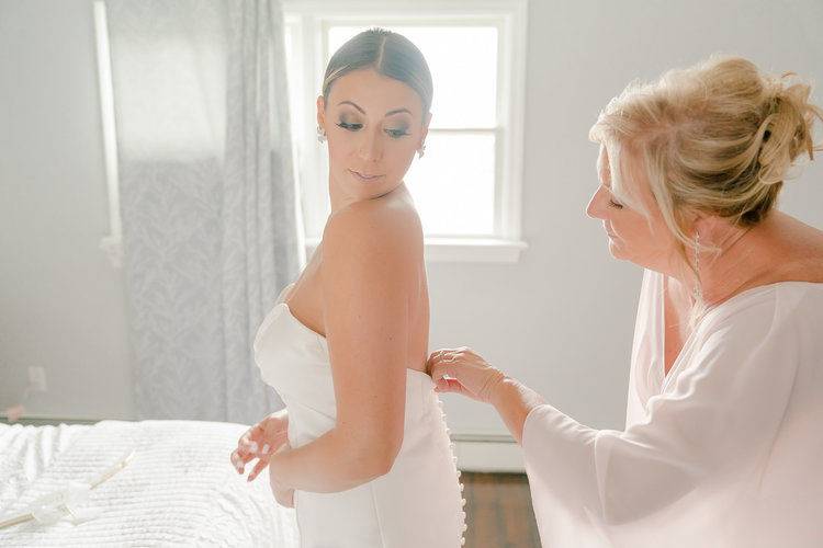A bride getting into her dress with a help from her mother  (Long Island, NY).