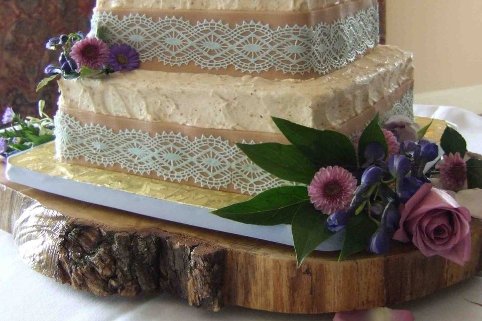 Rustic Blue Lace and Burlap Wedding Cake: Vegan Coconut-Pinapple Cake, Midnight Ganache ribbon, Lingonberry Jam ribbon, Almond Amaretto frosting and filling. Marzipan burlap and edible lace. Serves 155.