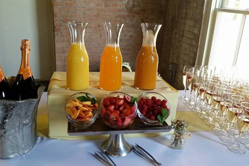 Mimosa bar with three flavors of orange juice and fresh fruit