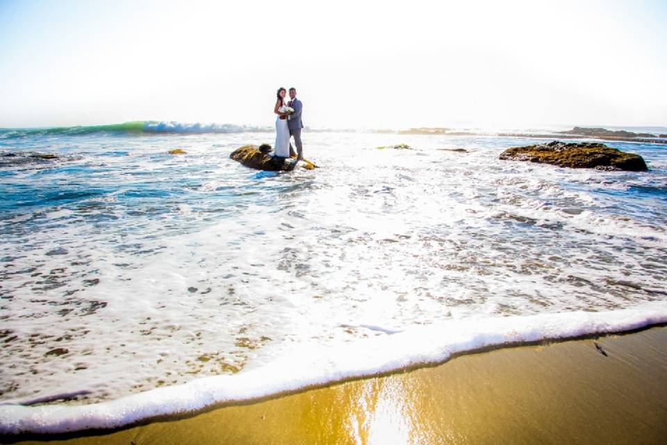 Couple standing on rock out in the water at a lovely high contrast colorer beach shot