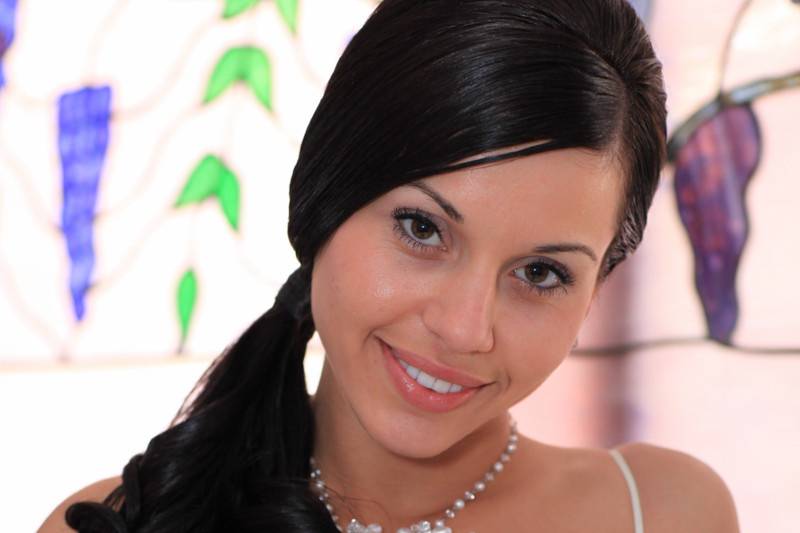 Bride posed before wedding with accenting colors behind her and holding bouquet.