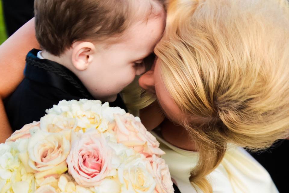 Bride and young ring bearer close together, with large yellow and pink bouquet