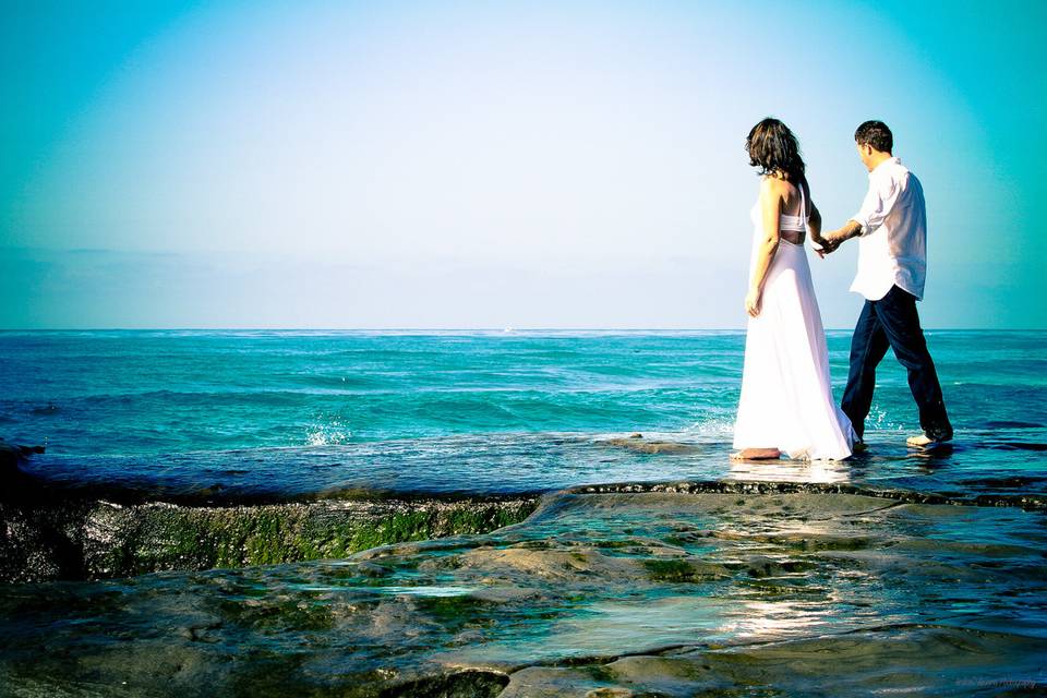 Couple holding hands walking on vivid colored sea cliff.