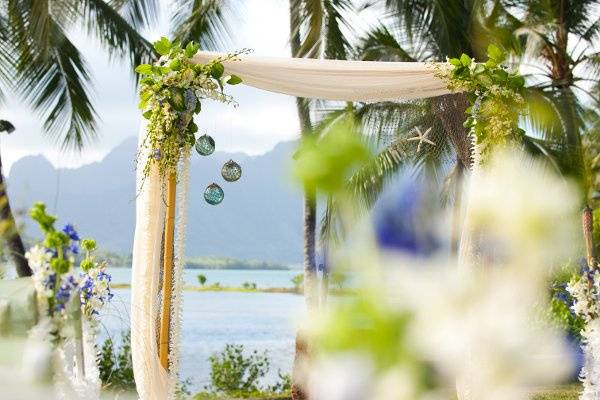 Vintage, Japanese, glass fishing floats adorn a bamboo arbor trimmed with accents of fishing net, reflecting the groom's love for diving and fishing.  Photo by Geralyn Camarillo of Hokuli'i Images.