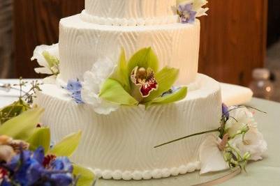 Light and delectable wedding cake made of fresh cream and beautifully adorned with green cymbidium orchids and sprigs of bear grass.  Photo by Geralyn Camarillo of Hokuli'i Images.
