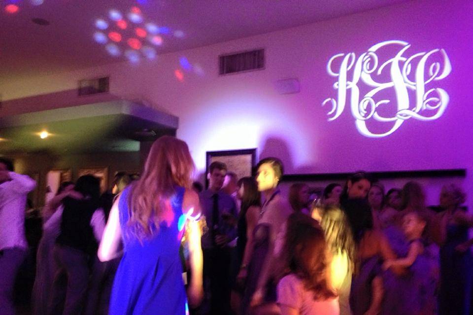 Guests dancing at a wedding reception at 5Eleven Palafox in Pensacola. You can see  the custom monogram, uplighting, and our 