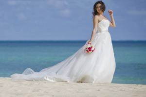 Bride alone portrait session in Hawaii at the beach on Oahu's east shore. blue green ocean scene with white sand and a chapel length dress.