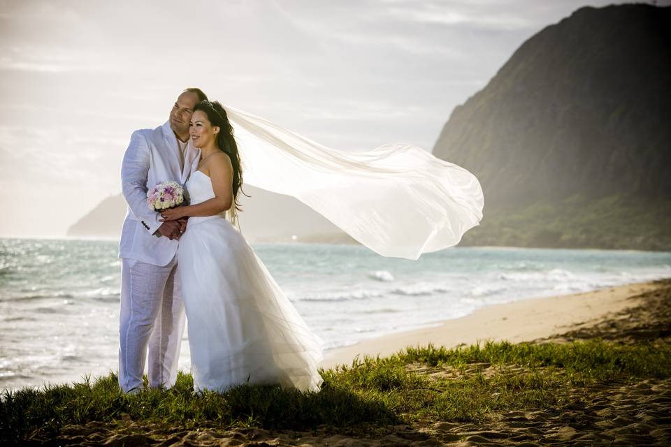Sunrise Beach Wedding Hawaii on Oahu's east shore at Waimanalo Bay, classic whites for the groom and a floor length off the shoulder dress with a long veil to catch the blowing trade winds.