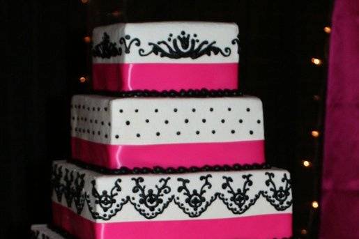 Hand piped black on white ButterCream with pink ribbon.