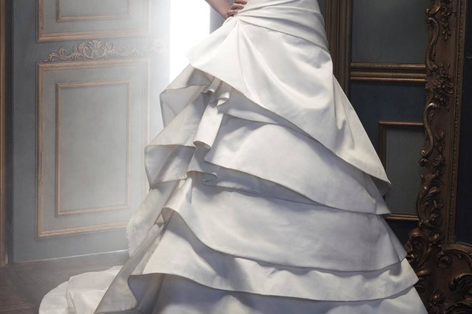 Style B068Italian Double Faced Duchess Silk Bodice has an asymmetrical neckline that flows into a full, A-line, ball gown. Skirt has several layers of double faced silk that cascades to create a beautiful back train.