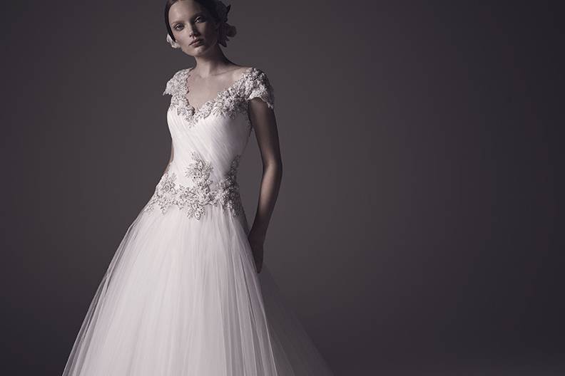 Style C104 Adriana  Adriana is an incredible tulle ball gown with a heavily beaded, heavily ruched bodice with hand beaded lace appliques that adorn the feminine cap sleeves of the v-shaped neckline.