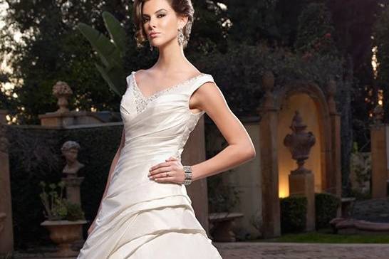 Style B018This gown was made to show off the bride’s figure. The Duchesse Silk shines as the A-line silhouette is accented by a beaded band that will display her tiny waist.