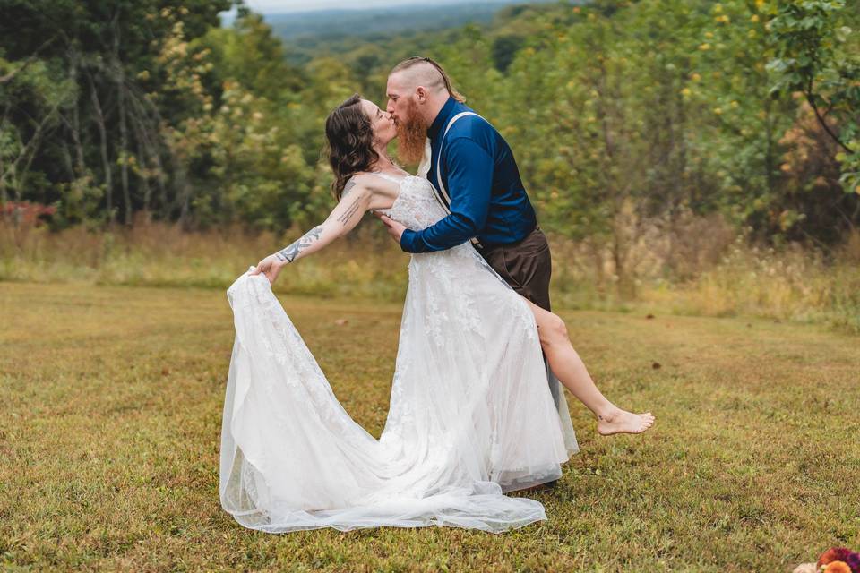 Groom dipping bride in woods