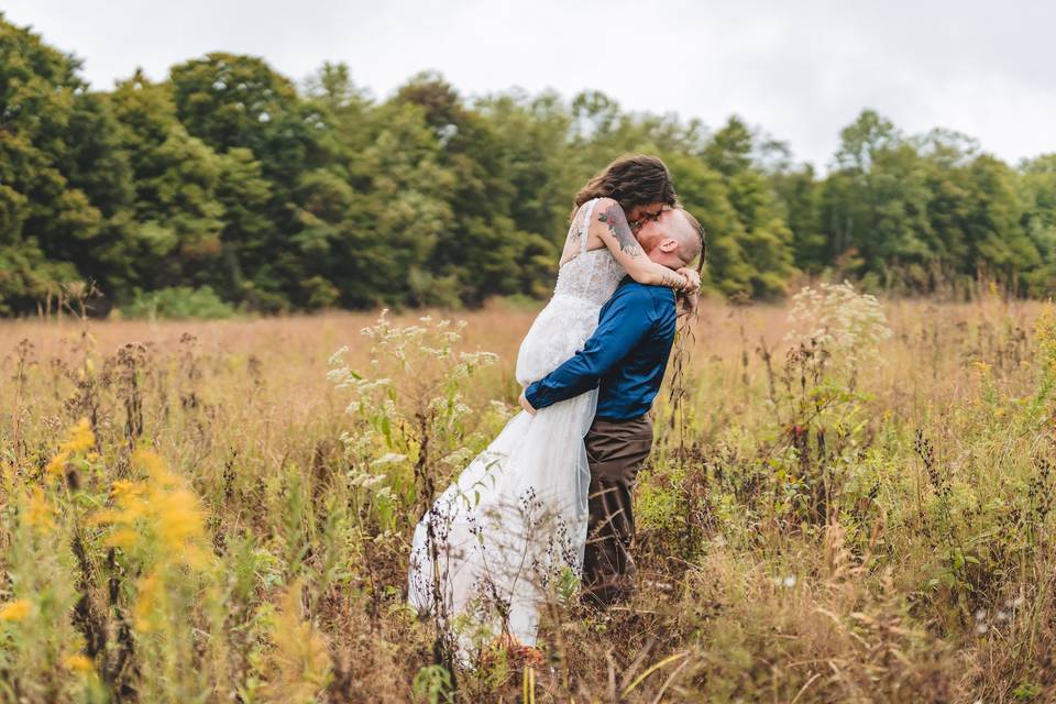 Groom lifting bride in field