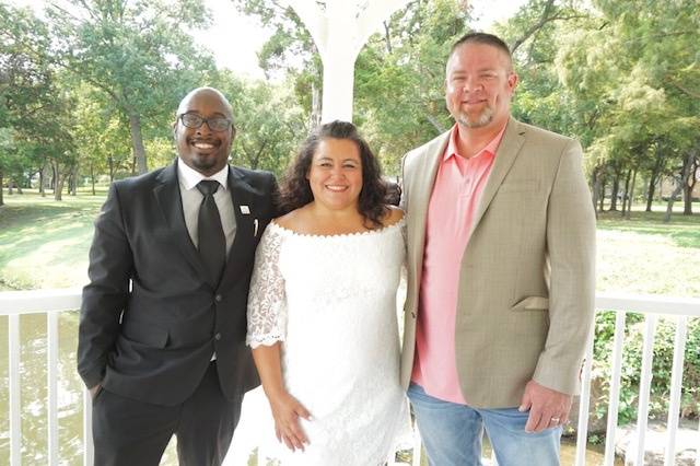 Smiling newlyweds and officiant