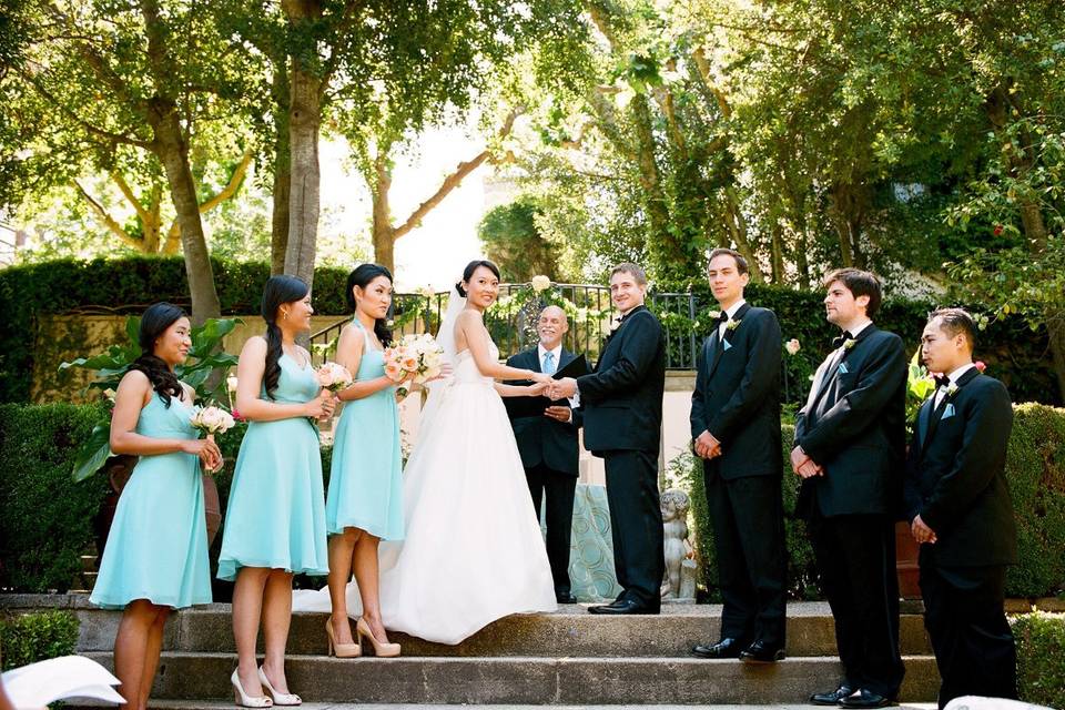 The outdoor ceremony was held in the formal gardens surrounding the French Chateau at the wedding venue.