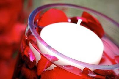 Romantic candles float over submerged red petals in the table centerpieces.