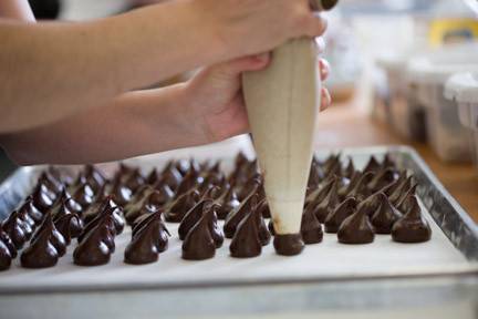 Piping truffle ganaches before they are weighed, rolled, and dipped in tempered chocolate.