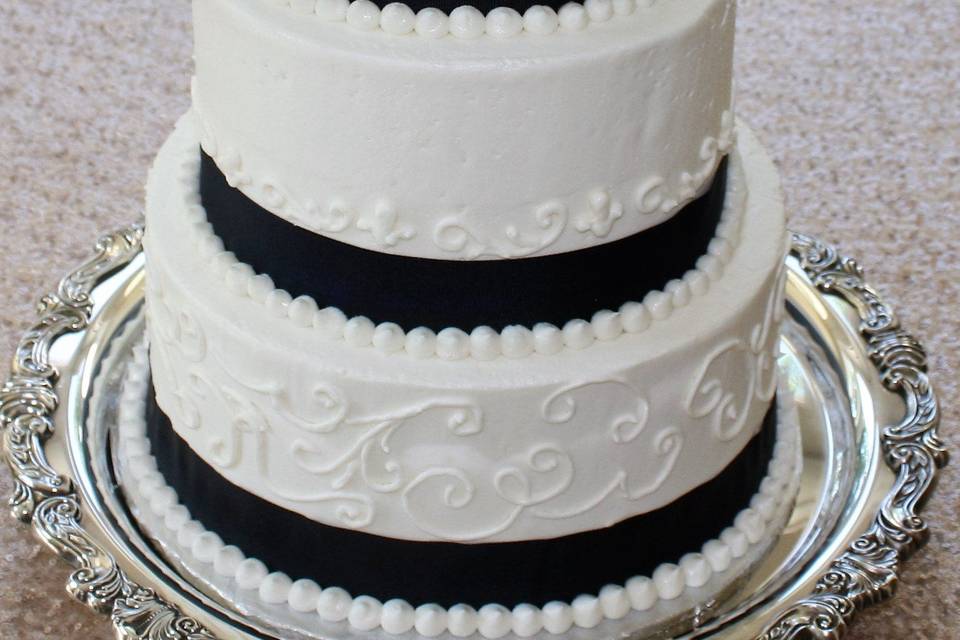 Wedding cake with black ribbons and flowers on top