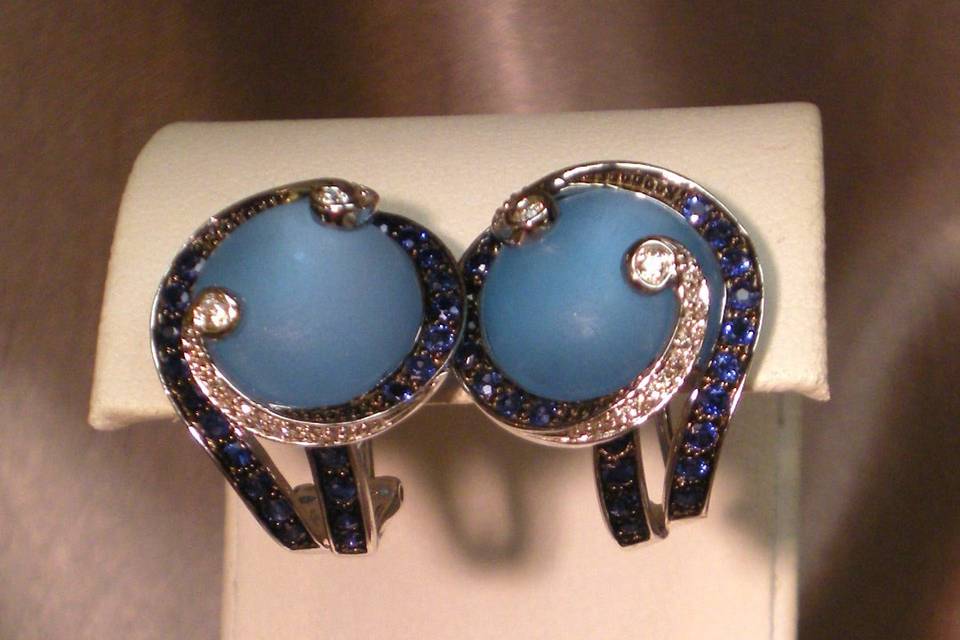These unique earrings are eye-catchers! The center stone is Blue Topaz. The swirling sides are made of 14K White Gold, Blue Sapphires, and Diamonds. When it comes to conversation starting pieces that are sure to make you the center of attention, Whidbey Jeweler has what it takes!