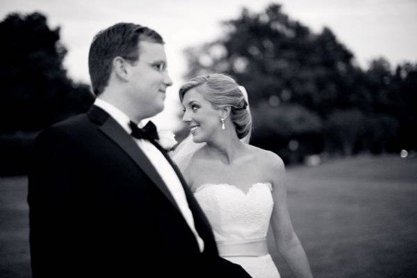 The bride looks over her shoulder at her bridesmaid while walking towards their reception hall.