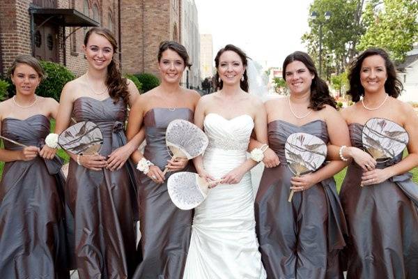 The bride with her bridesmaids carry vintage fans.