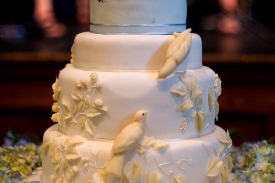 White chocolate doves and hand painted cocobutter painted bees adorn this pale blue and ivory wedding cake.