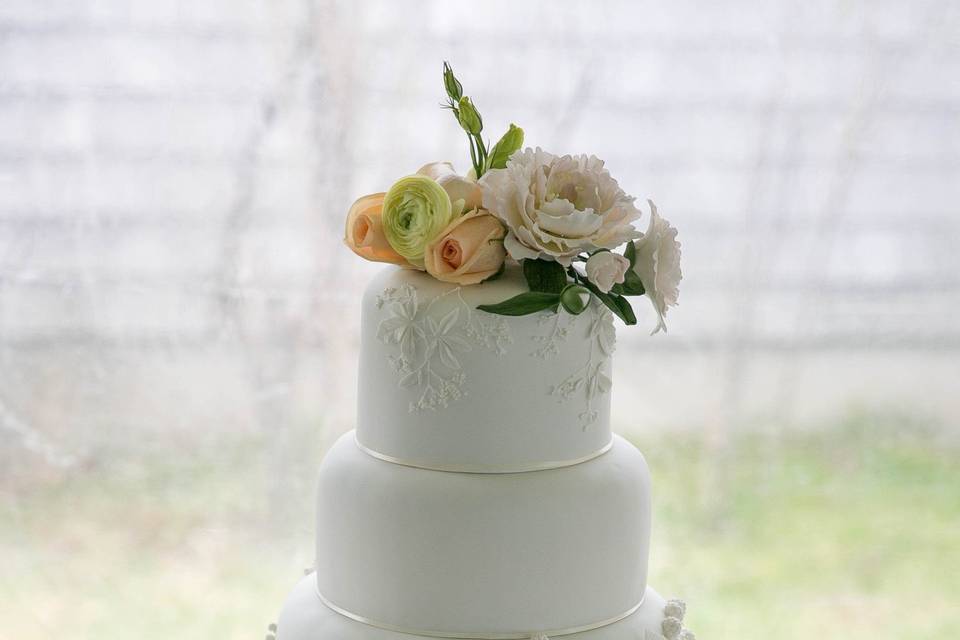 White on white botanical bas relief cake with coral roses