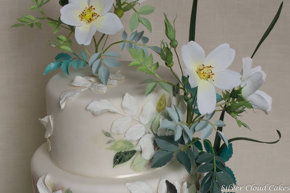Handcrafted beach roses with bas relief rose leaves, and cocoa butter handpainted details are exquisite on this stunning cake.