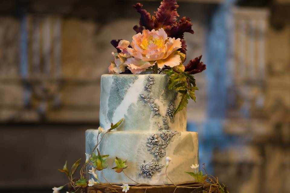Handcrafted sugar peonies and tulips adorn a wedding cake seemingly made of marble.