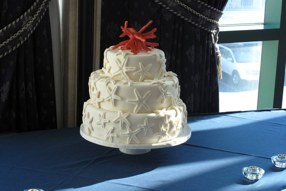 Handmade edible starfish covering this beautiful 3-tier cake with handmade edible coral on top