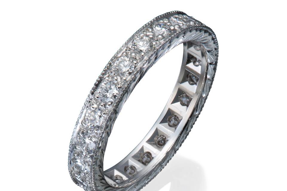 A platinum and diamond eternity band with hand engraving and milgrained edges.