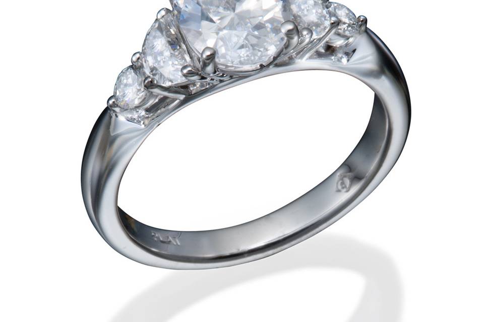 A classic diamond engagement ring with an oval diamond center, half moon, and round diamond accents on either side.