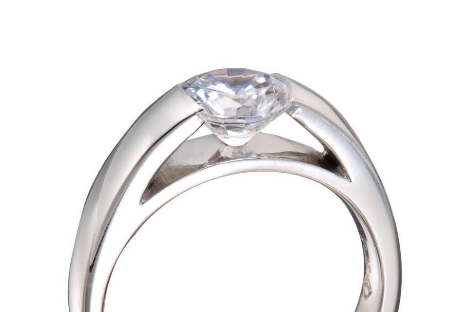 A modern engagement ring with a round diamond center stone and princess cut diamond accents.