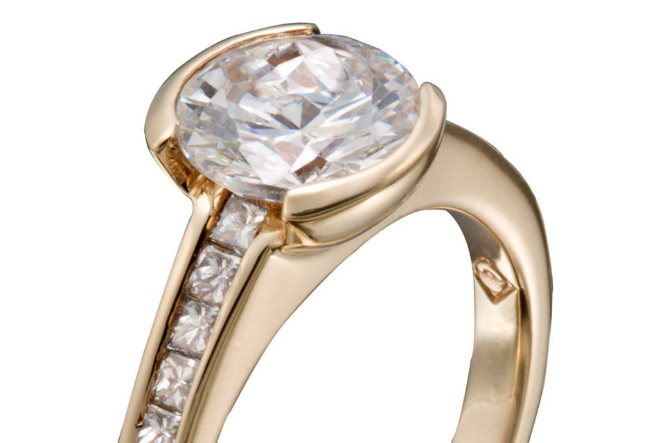 A modern engagement ring with a round diamond center stone and princess cut diamond accents.