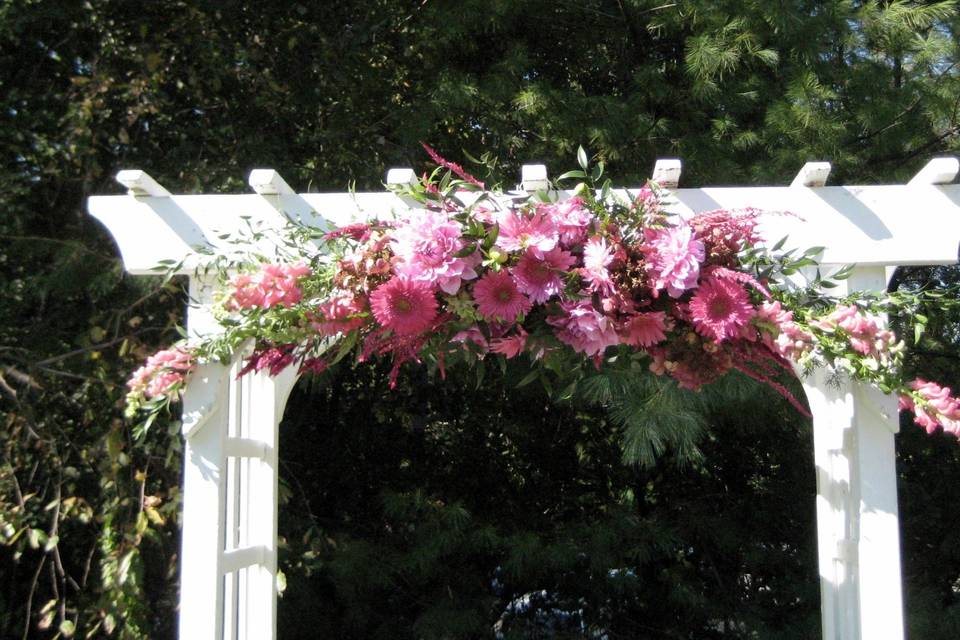 White arbor decorated in shades of pink, white and purple.