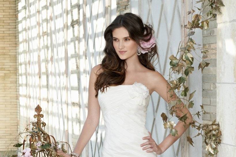 Style No. 41790-9346W <br>Short, sassy and ever-so-gorgeous are words that come to mind with one look at this short strapless wedding dress. And if you're on the fashion hunt for a look that's not only shorter than your traditional bridal style, but sultry and tapered to flatter your natural curves, this beauty undoubtedly stands as the clear choice to covet. The fabric is comprised of lush pleated taffeta with a side flower situated on the top left edge. It gives an extra dose of lovely to this classically, streamlined dress.